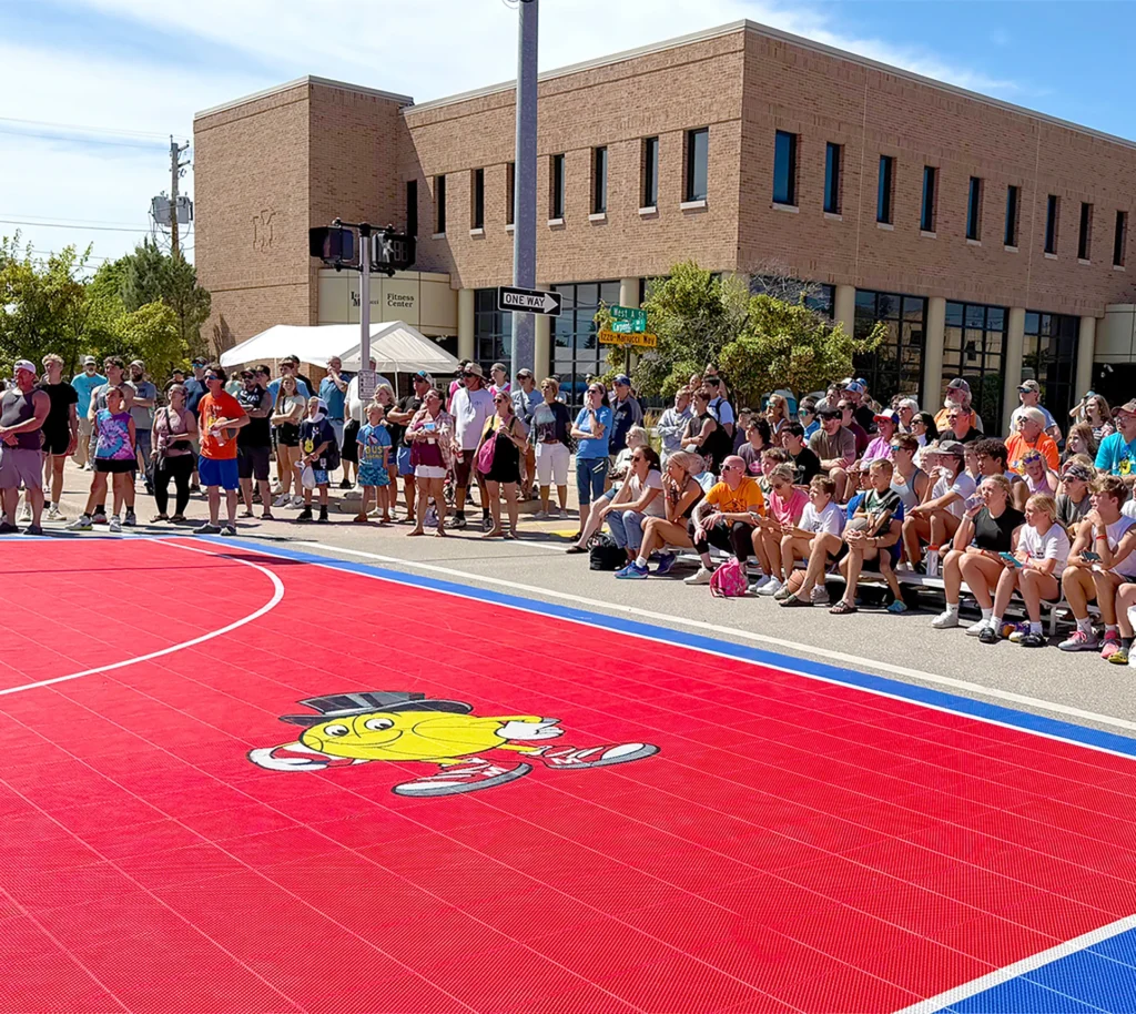 People gathered around red basketball court