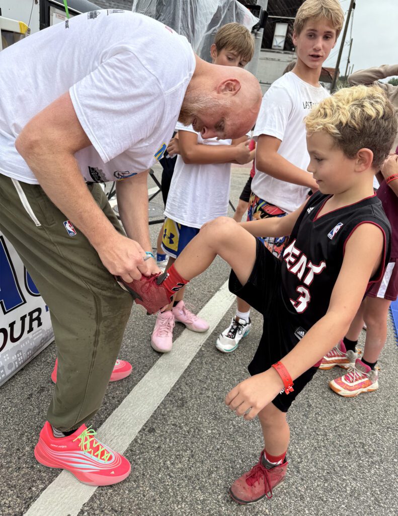 A man signs a young boy's arm at an outdoor event.