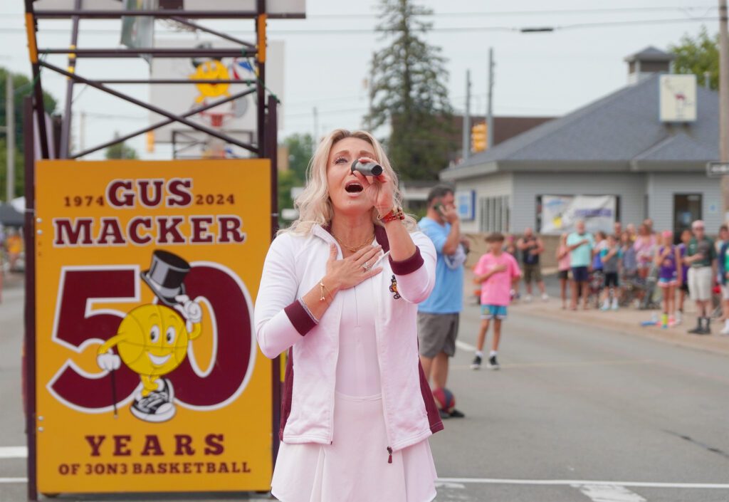 Woman in pink cheering at a street event.