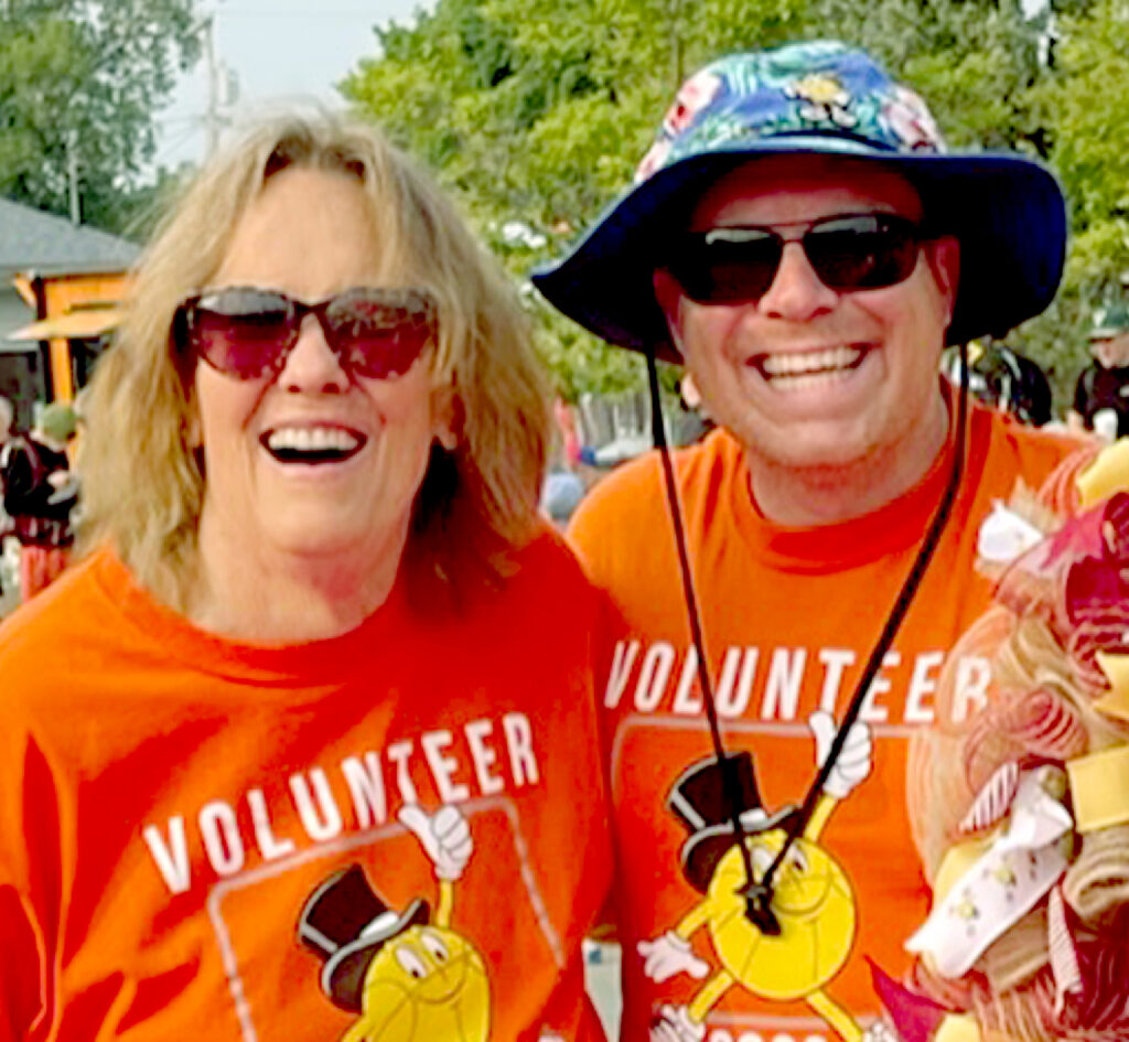 Two smiling volunteers in orange shirts